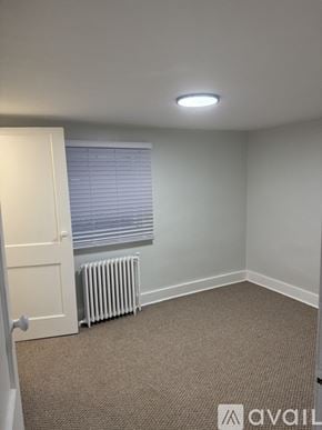 Berwyn apartment for rent - A carpeted room with a door, window, and a radiator.