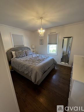 Narragansett house for rent - A bedroom with a large bed and a chandelier.