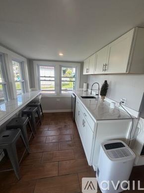 Narragansett house for rent - A kitchen with a table and chairs in the middle of it.