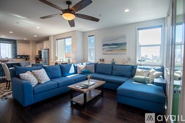 Oceanside townhouse for rent - A living room with a blue couch and a ceiling fan.