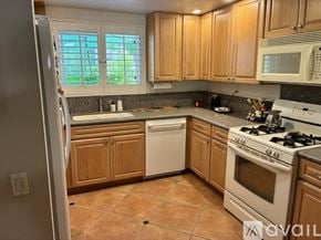 Palm Springs condo for rent - A kitchen with wooden cabinets and a white dishwasher.