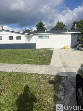 West Palm Beach house for rent - A white house with a grey roof and a black car parked in front.