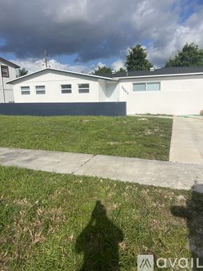 West Palm Beach house for rent - A white house with a grey roof and a black garage door.