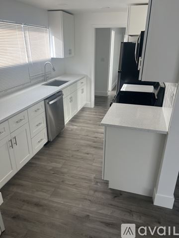 West Palm Beach house for rent - A kitchen with white cabinets and a wooden floor.