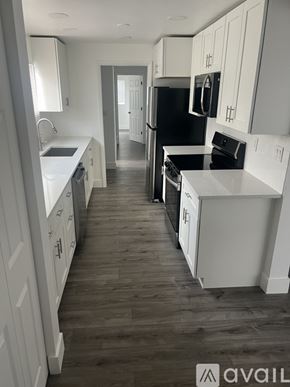 West Palm Beach house for rent - A kitchen with white cabinets and a black fridge.