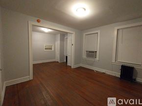 Baltimore apartment for rent - A hallway with a black door and wooden floor.