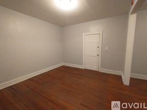 Baltimore apartment for rent - A room with a white door and a wooden floor.