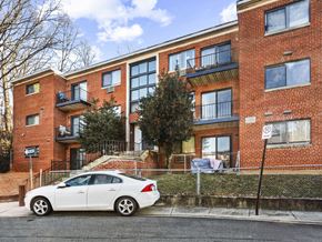 Washington apartment for rent - A white car is parked in front of a red brick apartment building.