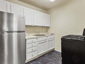 Washington apartment for rent - A kitchen with a stainless steel refrigerator, white cabinets, and a black stove top oven.