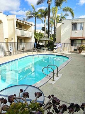 San Diego apartment for rent - A pool surrounded by a fence and palm trees.