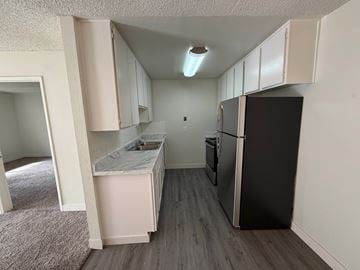 San Diego apartment for rent - A kitchen with a black refrigerator and white cabinets.