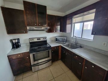 Brownsville apartment for rent - A kitchen with brown cabinets and a stove top oven.
