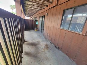 Brownsville apartment for rent - A long corridor with a fence on the left and a building on the right.