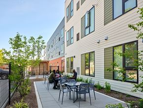 Detroit apartment for rent - A group of people are sitting at a table outside of a building.