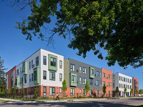 Detroit apartment for rent - A row of modern townhouses with green trees in the foreground.