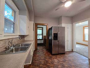 East Chicago house for rent - A kitchen with a sink, refrigerator, and wooden floors.