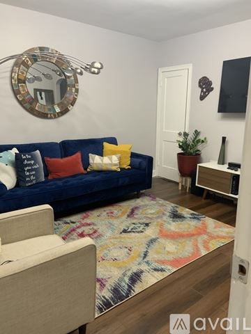 Washington apartment for rent - A living room with a blue couch and a round mirror on the wall.