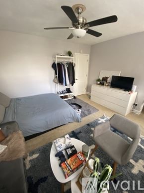 Washington apartment for rent - A bedroom with a bed, a chair, a table with snacks, and a ceiling fan.