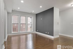 Chicago apartment for rent - A spacious room with wooden floors and a large window.