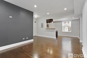 Chicago apartment for rent - A spacious room with wooden flooring and a large window.