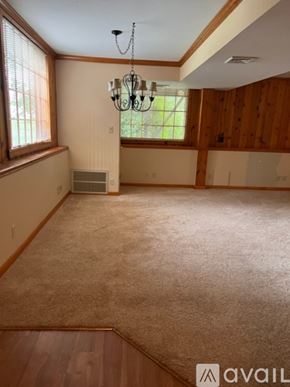 Pittsburgh apartment for rent - A room with a carpet, wooden walls, and a chandelier.