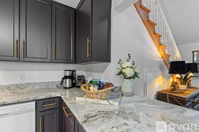 Tallahassee townhouse for rent - A kitchen with black cabinets and a marble countertop.