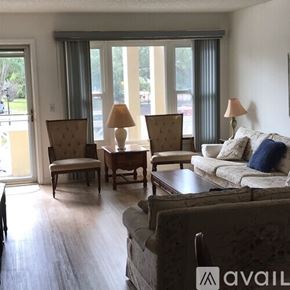 Clearwater condo for rent - A living room with a television, two chairs, a couch, and a window with a view of the outdoors.