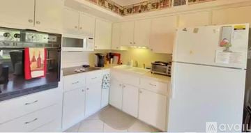 Clearwater condo for rent - A kitchen with white cabinets and appliances, including a refrigerator, microwave, and oven.