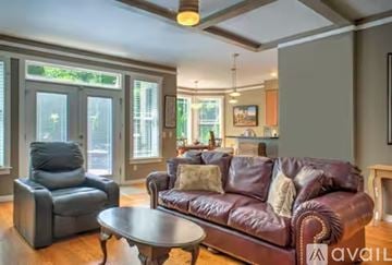 Asheville house for rent - A living room with a brown leather couch and a grey armchair.