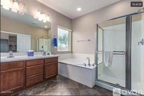 Phoenix house for rent - A modern bathroom with a large mirror, double sinks, and a glass shower door.