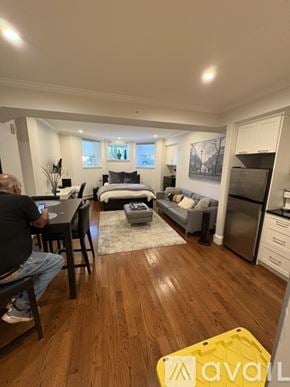 Boston apartment for rent - A man is sitting at a desk in a room with wooden floors and a bed in the background.