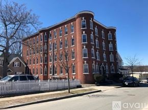 Worcester apartment for rent - A large red brick building with a white picket fence in front.