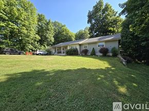 Vine Grove apartment for rent - A house with a well-maintained lawn and trees in the background.