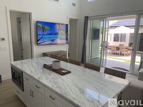 Huntington Beach apartment for rent - A modern kitchen with a marble countertop and a television displaying a beach scene.