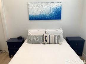 Huntington Beach apartment for rent - A bedroom with a white bed, a blue painting, and two navy blue nightstands.