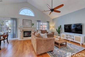 Myrtle Beach house for rent - A living room with a beige couch, a fireplace, a ceiling fan, and a television.