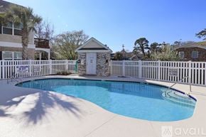 Myrtle Beach house for rent - A pool surrounded by a white fence with a small building in the background.