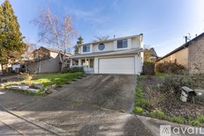 Beaverton house for rent - A spacious room with a carpeted floor, a staircase with wooden railings, and a door leading to another room.