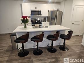 Tooele townhouse for rent - A kitchen with a white island and four bar stools.