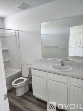 Tooele townhouse for rent - A bathroom with a toilet, sink, and mirror.