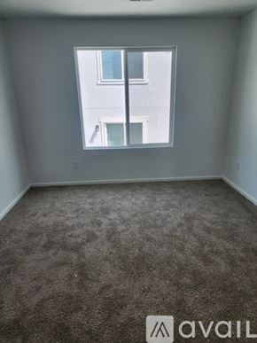Tooele townhouse for rent - A carpeted room with a window overlooking a building.
