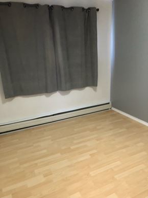 Swift Current apartment for rent - A grey curtain hangs on a white wall above a wooden floor.