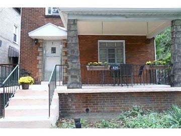 Pittsburgh house for rent - A red brick house with a white door and a small porch.