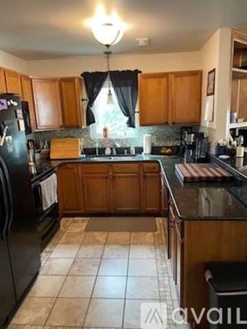 Sheridan townhouse for rent - A kitchen with wooden cabinets and black appliances.