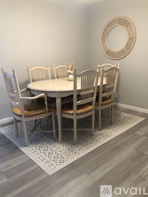 Anacortes apartment for rent - A dining room with a round mirror and a white table with chairs around it.