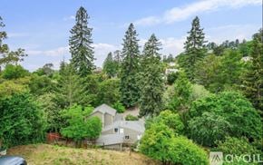 Oakland apartment for rent - A house is surrounded by trees in a wooded area.