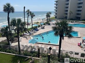 New Smyrna Beach condo for rent - A pool area with people swimming and sunbathing.
