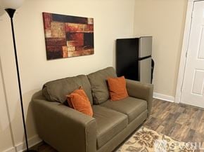 North Little Rock apartment for rent - A brown couch with two pillows sits in a room with a black fridge and a painting on the wall.