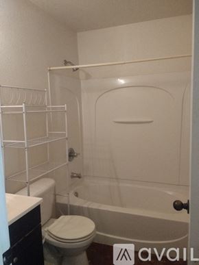 Fort Worth apartment for rent - A bathroom with a toilet, a bathtub, and a towel rack.