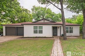Lake Worth house for rent - A house with a brown roof and a white exterior is surrounded by greenery.
